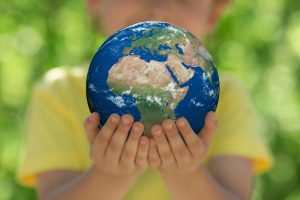 Child,Holding,3d,Planet,In,Hands,Against,Green,Blurred,Background.
